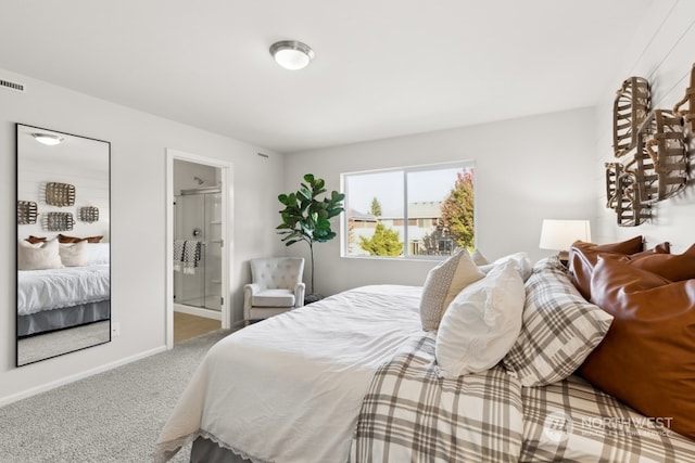 carpeted bedroom with ensuite bath and baseboards