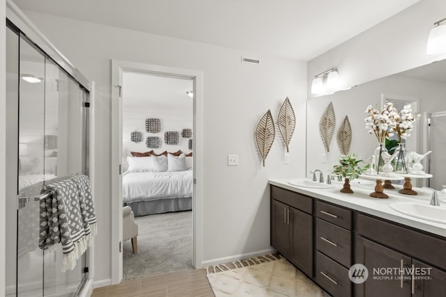 ensuite bathroom featuring double vanity, visible vents, a shower stall, and a sink