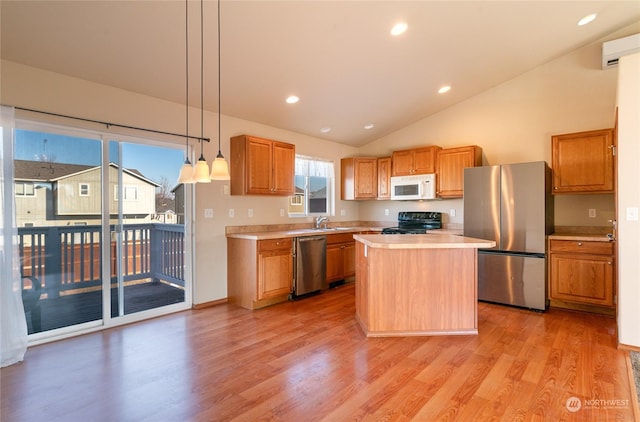 kitchen featuring sink, a kitchen island, pendant lighting, stainless steel appliances, and light hardwood / wood-style floors