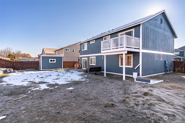 snow covered property with a balcony and a storage shed