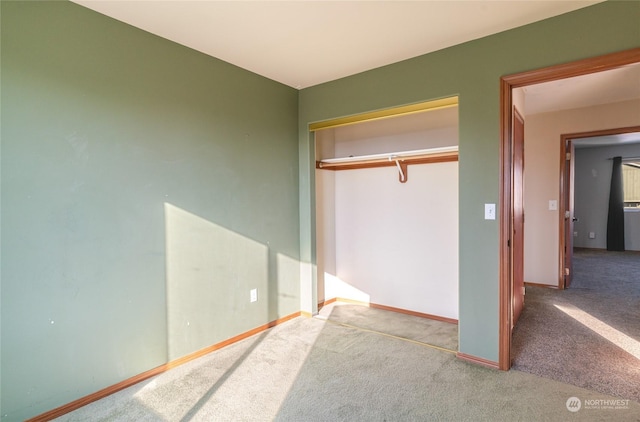 unfurnished bedroom with light colored carpet and a closet