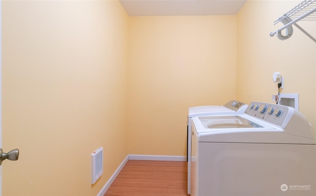 clothes washing area featuring washing machine and dryer and light wood-type flooring