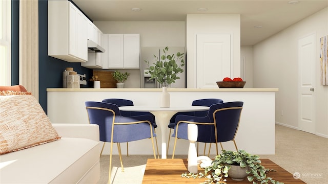 kitchen featuring light carpet, a breakfast bar area, and white cabinets