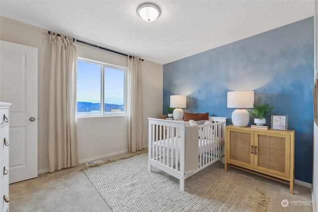 bedroom featuring a mountain view, a crib, and light colored carpet