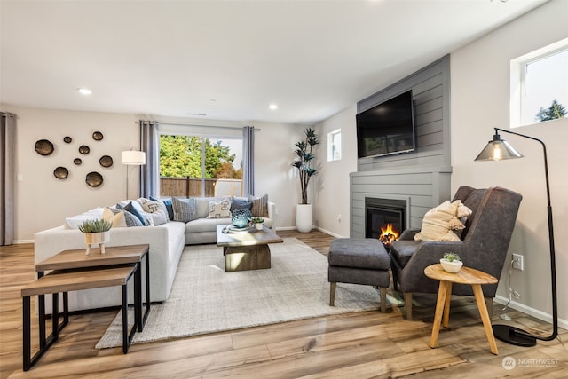 living room with light hardwood / wood-style floors and a large fireplace