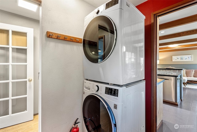 laundry room featuring stacked washing maching and dryer and light hardwood / wood-style floors