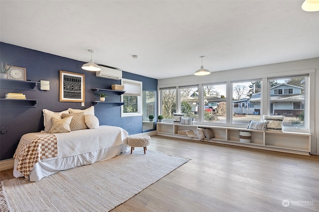 bedroom featuring a wall mounted AC and light wood-type flooring