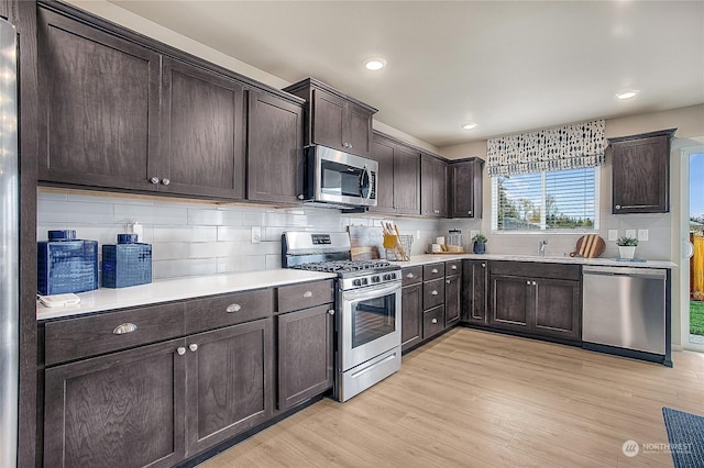 kitchen with sink, decorative backsplash, stainless steel appliances, dark brown cabinets, and light wood-type flooring