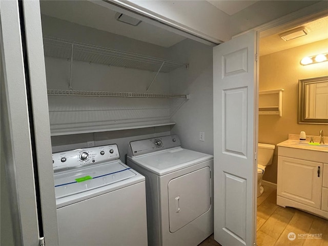 clothes washing area with washing machine and dryer, sink, and light hardwood / wood-style flooring