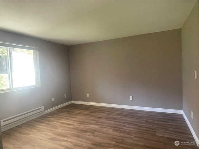 empty room featuring a baseboard heating unit and hardwood / wood-style floors