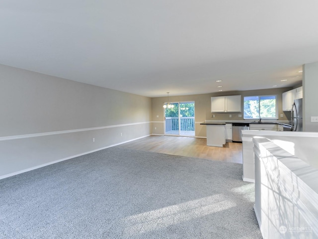 kitchen with white cabinetry, a healthy amount of sunlight, pendant lighting, light colored carpet, and stainless steel appliances