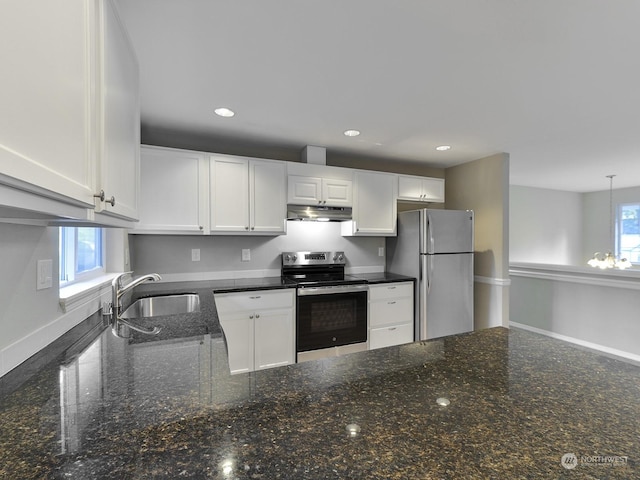 kitchen featuring appliances with stainless steel finishes, white cabinetry, sink, dark stone counters, and hanging light fixtures