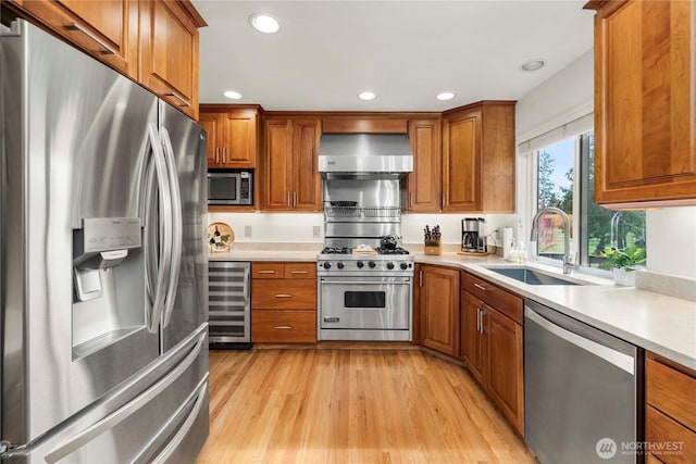 kitchen with beverage cooler, brown cabinets, appliances with stainless steel finishes, wall chimney exhaust hood, and a sink