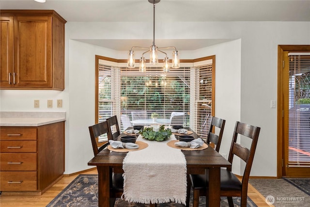 dining room featuring light wood-type flooring, baseboards, and an inviting chandelier