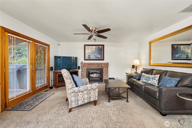 carpeted living area with visible vents, a brick fireplace, and ceiling fan