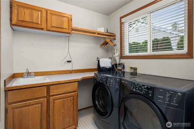 washroom with cabinet space, independent washer and dryer, and a sink