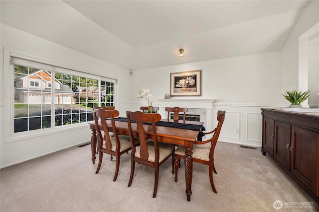 dining area featuring wainscoting, visible vents, light colored carpet, and a decorative wall