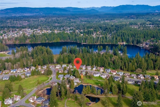 drone / aerial view with a forest view and a water and mountain view