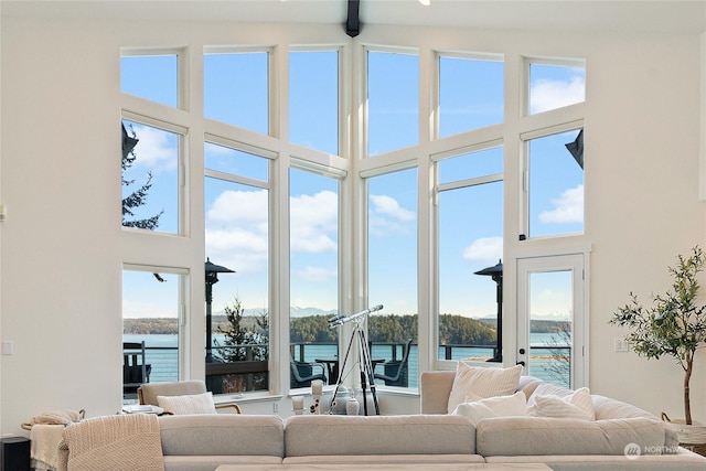 living room with a towering ceiling, beamed ceiling, and a water view