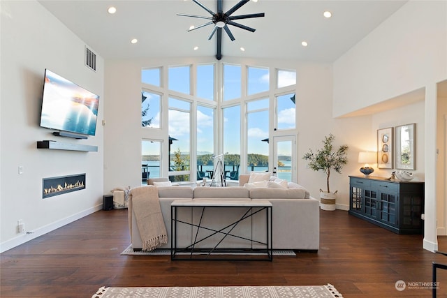 living room featuring high vaulted ceiling, dark hardwood / wood-style floors, and a water view