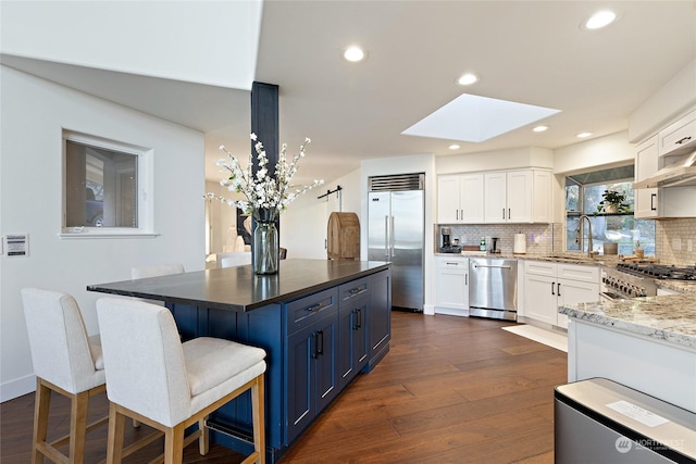 kitchen featuring a breakfast bar area, stainless steel appliances, white cabinets, and blue cabinets