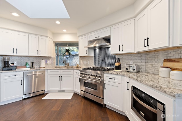 kitchen with white cabinetry, stainless steel appliances, light stone countertops, and exhaust hood