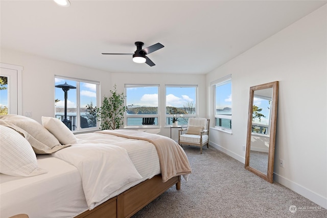 bedroom featuring carpet flooring, ceiling fan, and a water view