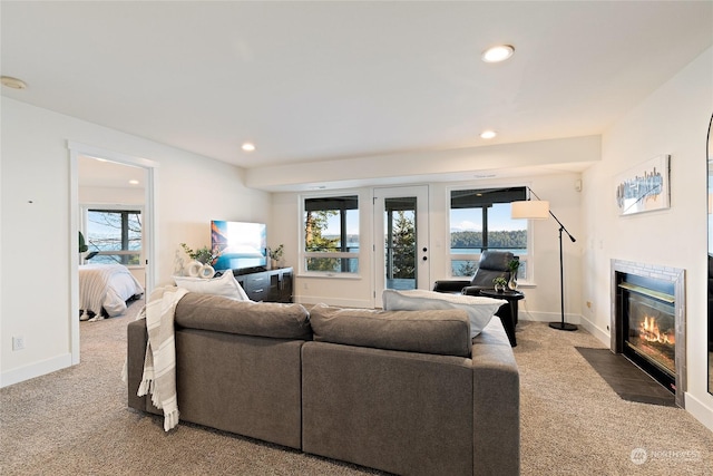 living room featuring a healthy amount of sunlight, a tiled fireplace, and carpet