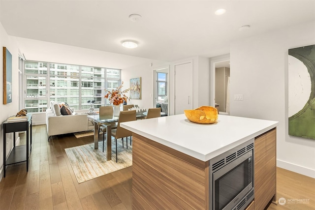 kitchen with stainless steel microwave, wood-type flooring, and a kitchen island