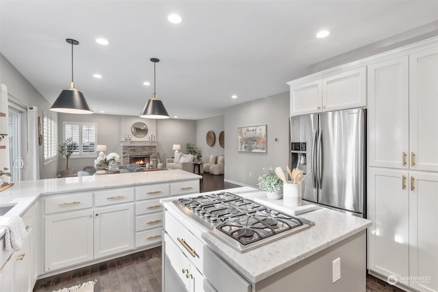 kitchen featuring white cabinetry, pendant lighting, a fireplace, and stainless steel appliances