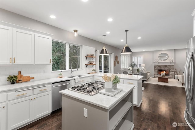 kitchen featuring sink, a kitchen island, stainless steel appliances, light stone countertops, and white cabinets