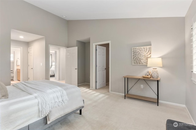 bedroom with ensuite bath, high vaulted ceiling, and light carpet