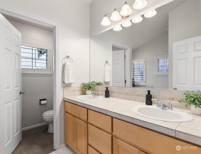 bathroom with vanity, vaulted ceiling, parquet floors, and toilet