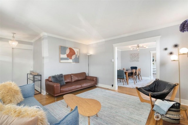 living room with a notable chandelier, crown molding, and light wood-type flooring