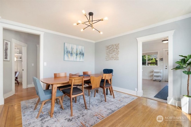 dining space with ornamental molding, a chandelier, and light hardwood / wood-style floors