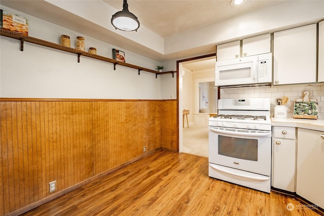 kitchen featuring white cabinetry, light hardwood / wood-style flooring, wooden walls, white appliances, and backsplash