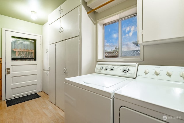 laundry room featuring cabinets, washer and clothes dryer, and light wood-type flooring