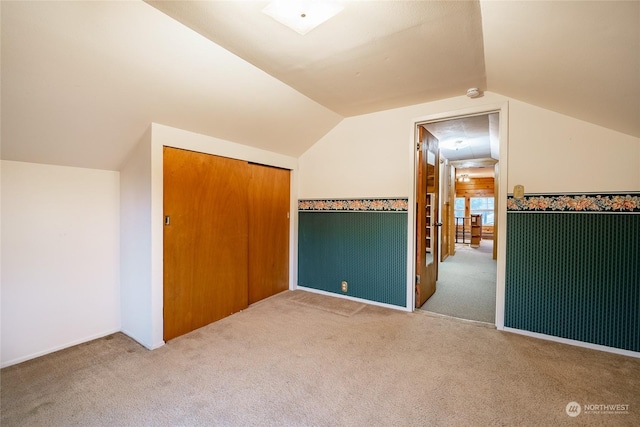 bonus room with vaulted ceiling and light carpet