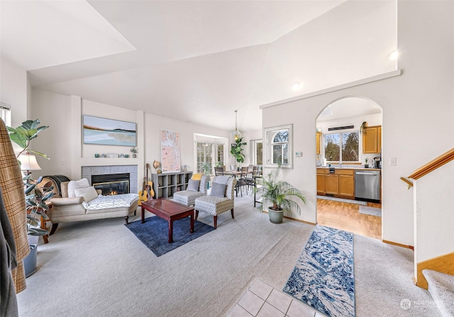 carpeted living room featuring plenty of natural light, a tiled fireplace, and vaulted ceiling