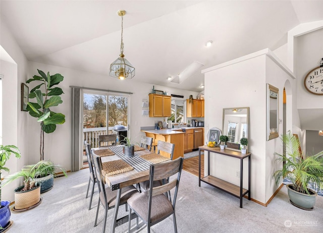 dining room featuring vaulted ceiling and light carpet