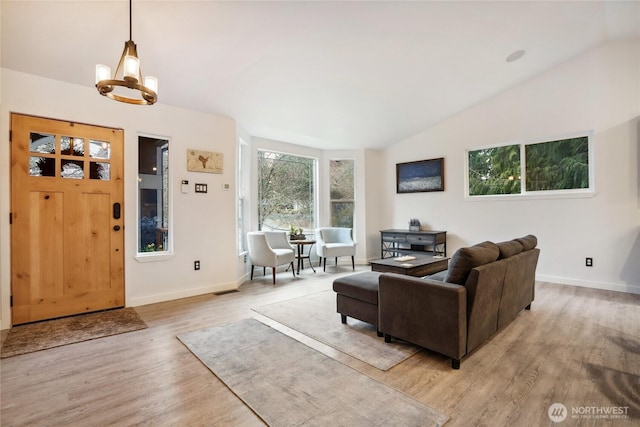 living area featuring light wood-type flooring, visible vents, a notable chandelier, baseboards, and vaulted ceiling