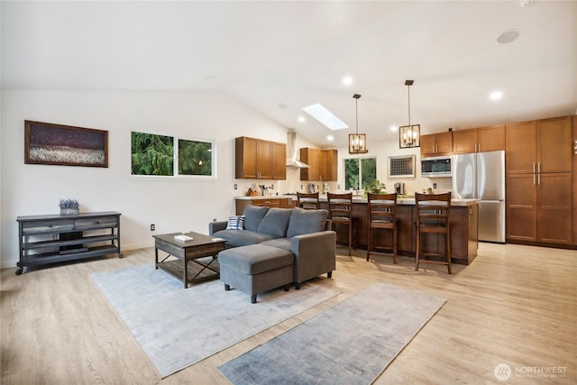 living room featuring a wealth of natural light, light wood-type flooring, and vaulted ceiling with skylight