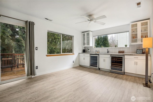 kitchen featuring decorative backsplash, wine cooler, light wood-style flooring, and white cabinetry