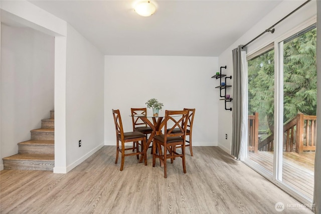 dining space with stairway, baseboards, and light wood-type flooring