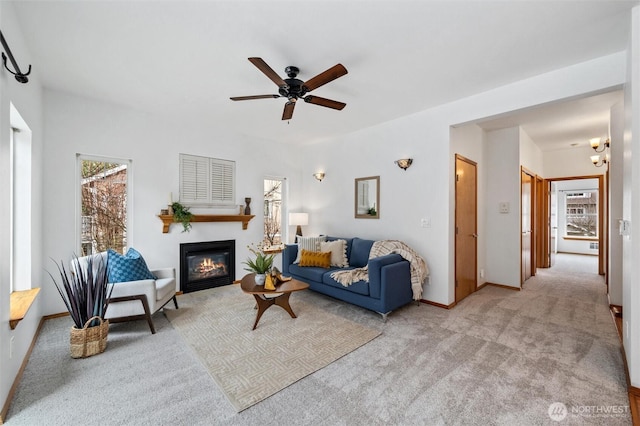 living room with ceiling fan, carpet floors, a glass covered fireplace, and baseboards