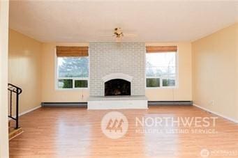 unfurnished living room with a baseboard radiator, wood-type flooring, and a fireplace