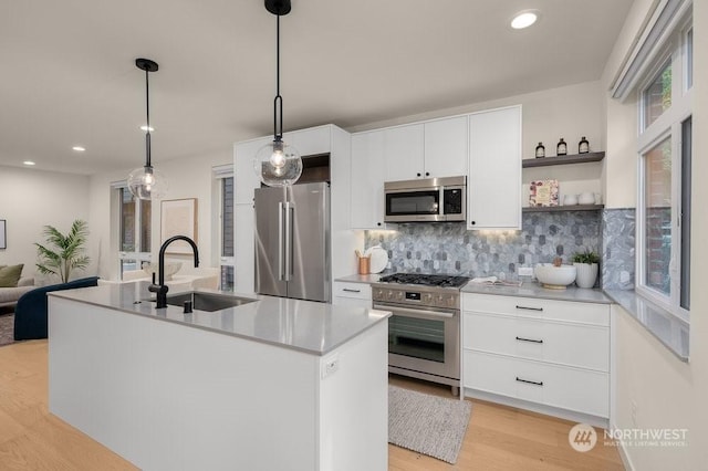 kitchen featuring pendant lighting, white cabinetry, sink, a kitchen island with sink, and stainless steel appliances