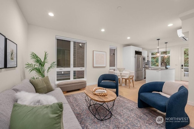 living room with sink, light hardwood / wood-style flooring, and an AC wall unit