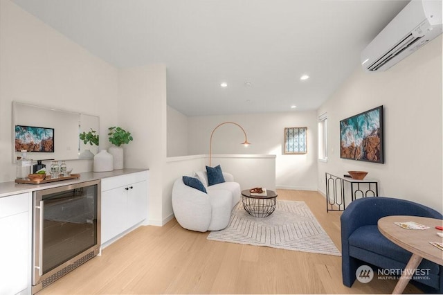 sitting room featuring indoor bar, light wood-type flooring, wine cooler, and a wall unit AC