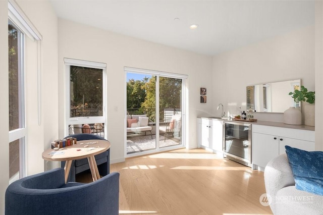 interior space with wine cooler, indoor wet bar, and light hardwood / wood-style flooring